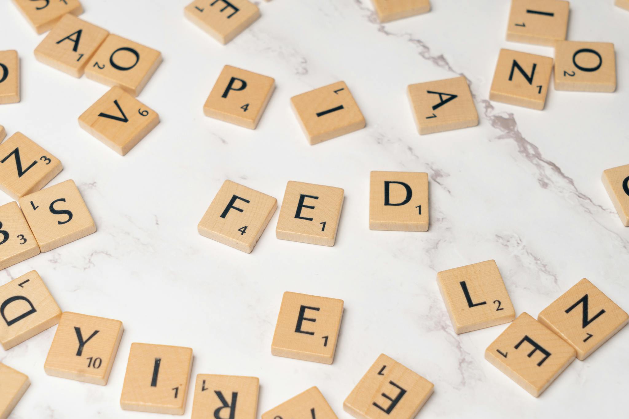 Scrabble tiles arranged to spell 'FED' on a marble surface, symbolizing finance.
